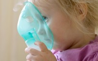 Una niña sostiene una máscara nebulizadora de plástico, hecha de plástico de policarbonato, frente a su cara.